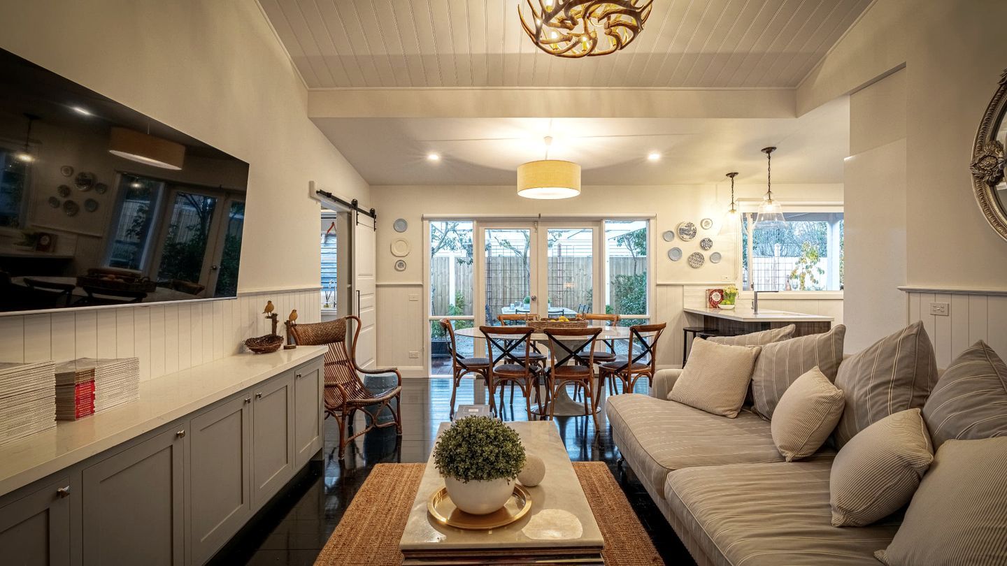 Une cuisine moderne avec des meubles blancs, un coin repas comprenant une table et des chaises, et un salon avec un canapé et une table basse.