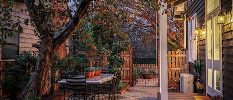 A patio with a table and chairs, surrounded by plants and a wooden fence.