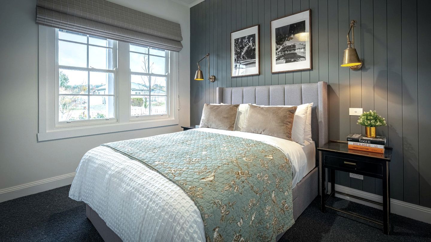 A bedroom with a bed, a nightstand, a lamp, and two framed pictures on the wall.