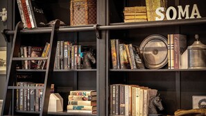 A bookshelf with books, a horse figurine, and a metal container.