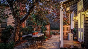 A patio with a table and chairs, surrounded by plants and a wooden fence.