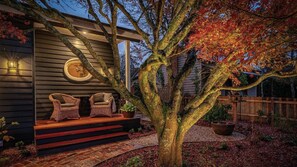 A house with a porch, two wicker chairs, a potted plant, and a wooden fence.