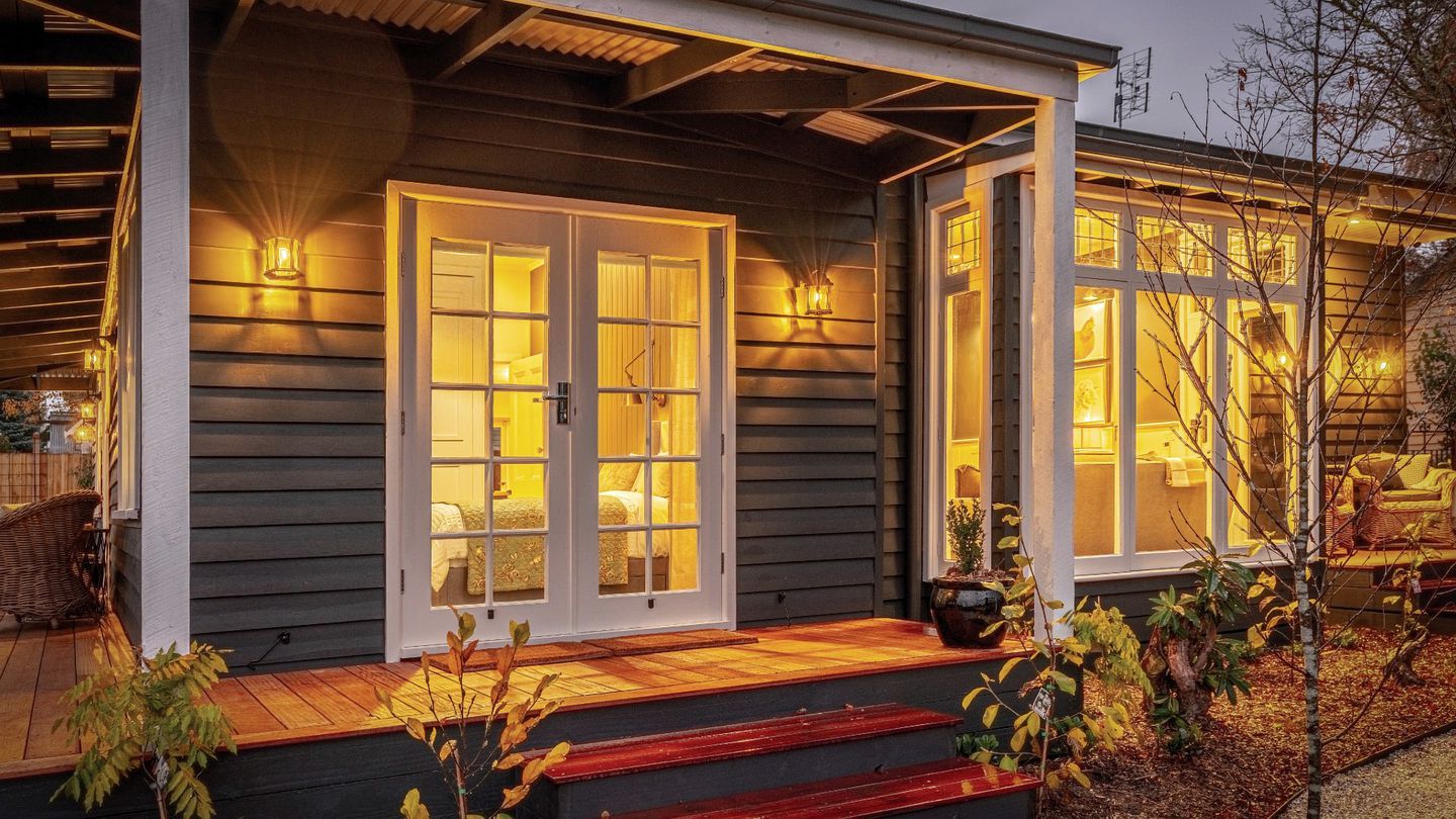 A house with a porch, a set of double doors, and a small garden area with plants.