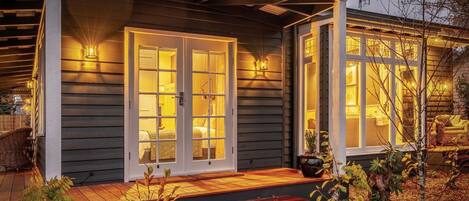 A house with a porch, a set of double doors, and a small garden area with plants.