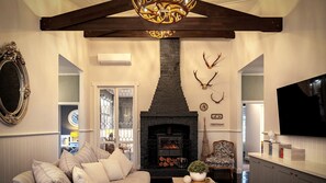 A cozy living room with a fireplace, a sofa, and decorative antlers on the wall.