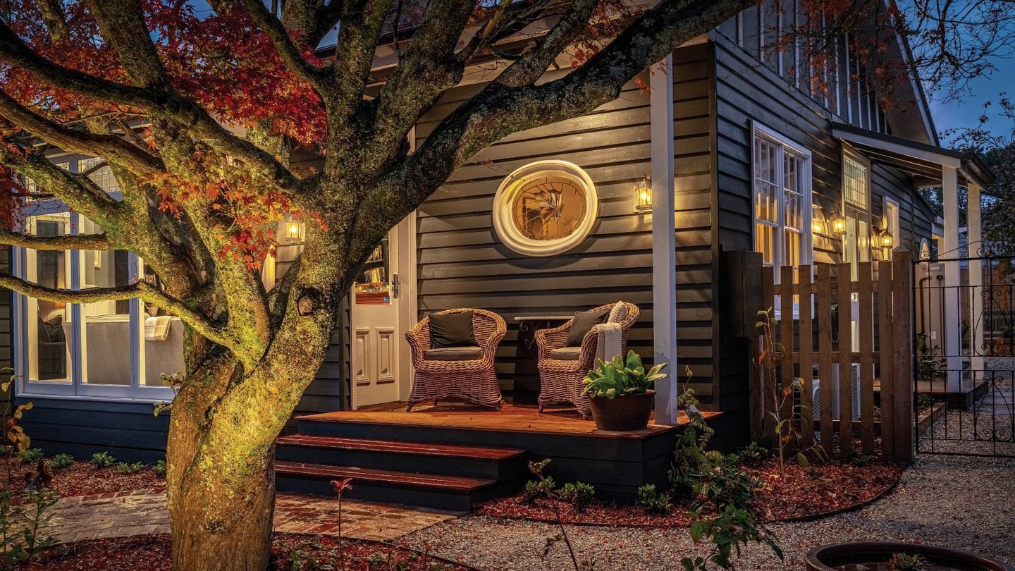 A house with a porch, two wicker chairs, a potted plant, and a circular window.
