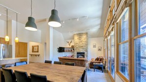 Eine moderne Küche mit Steinwand, ein Essbereich mit Holztisch und -stühlen sowie eine gemütliche Sitzecke mit Kamin.