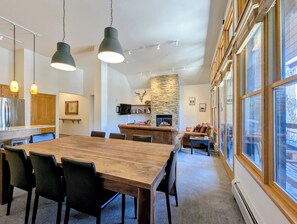 Eine moderne Küche mit Steinwand, ein Essbereich mit Holztisch und -stühlen sowie eine gemütliche Sitzecke mit Kamin.