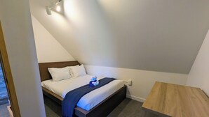 Ein Schlafzimmer mit einem Bett, einem Nachttisch, einer hölzernen Bank und einer Deckenleuchte.