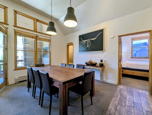 Ein Essbereich mit Holztisch und Stühlen, einem Gemälde eines Stiers und einem Bett mit Blick.