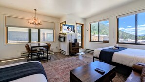 A hotel room with two beds, a TV, a dining area, and large windows with mountain views. - New Listing | Updated | Walk to Slopes (Keystone)