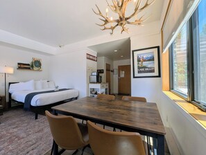 A hotel room with a bed, a dining table with chairs, a chandelier, a framed picture, and a window with a view. - New Listing | Updated | Walk to Slopes (Keystone)