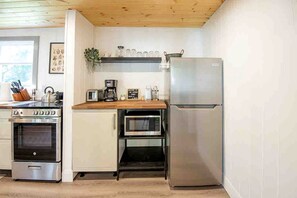 A compact kitchen with a stove, microwave, and refrigerator. - Stunning Cottage with Fireplace in Lawartha Lakes, Ontario (Kawartha Lakes)