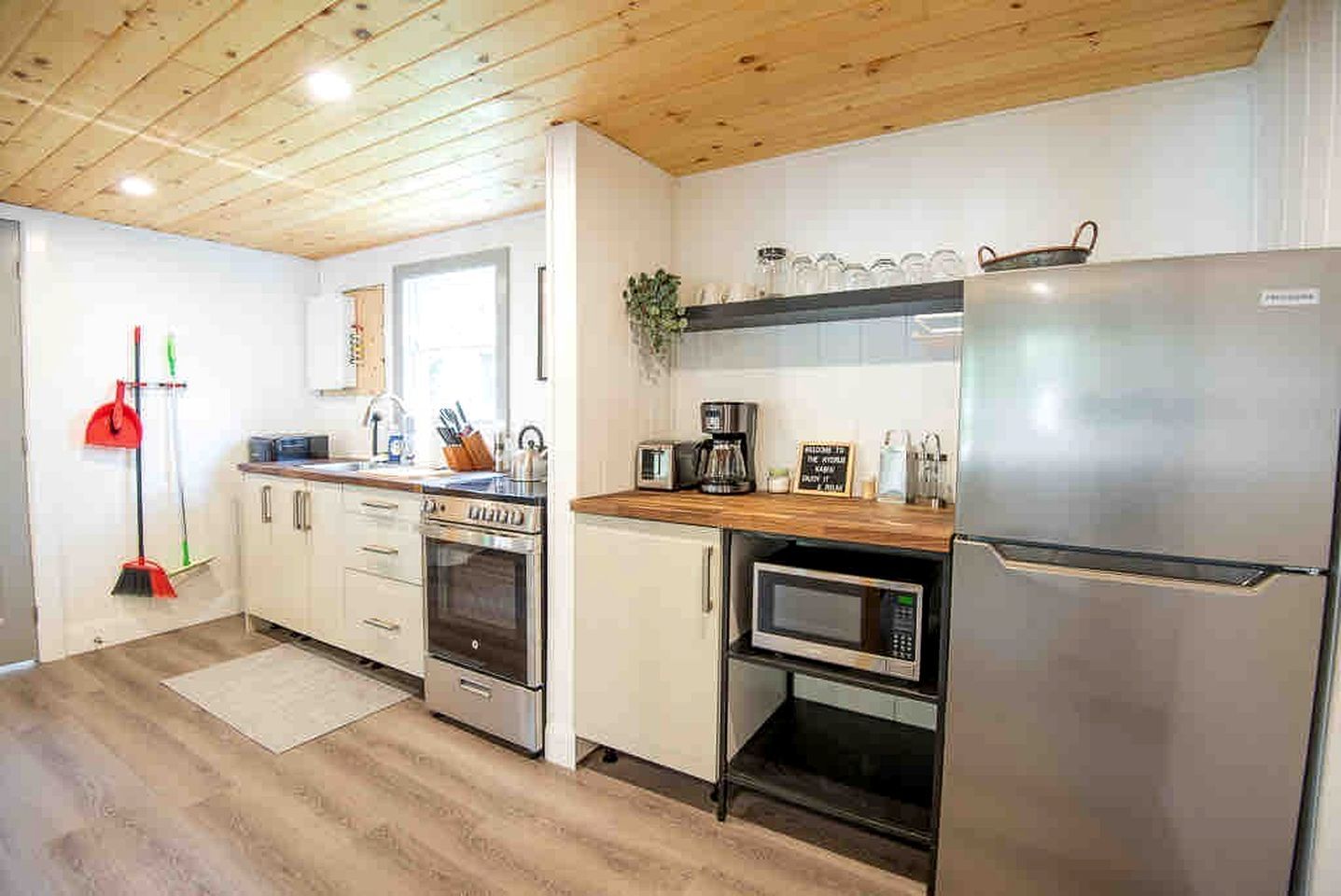 Eine moderne Küche mit einem Edelstahl-Kühlschrank, einer Mikrowelle, einem Backofen und einer Kaffeemaschine.