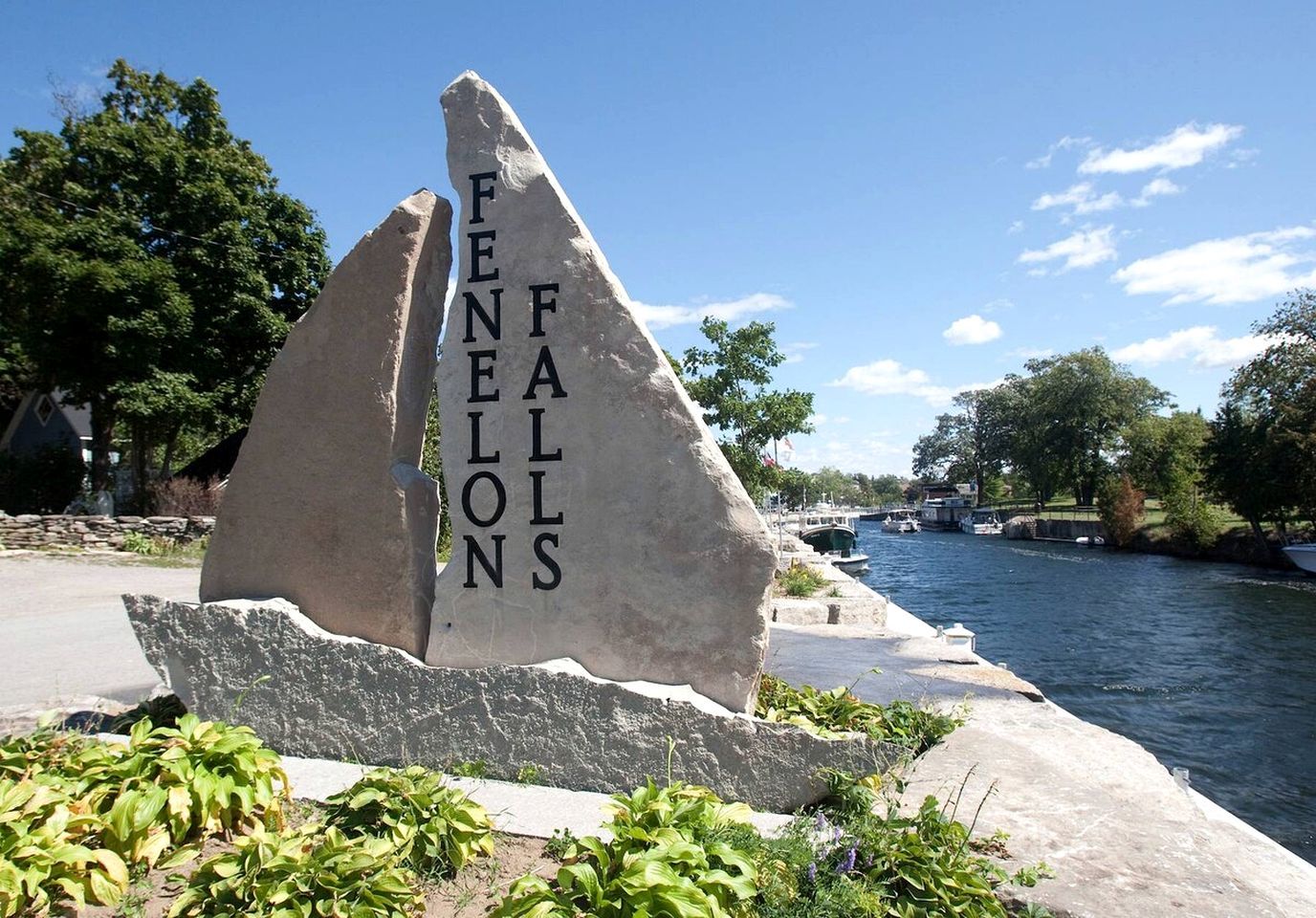 Ein Steins Denkmal mit der Inschrift 'FENELONS' in einer Parkanlage, im Hintergrund ein Fluss und Boote.