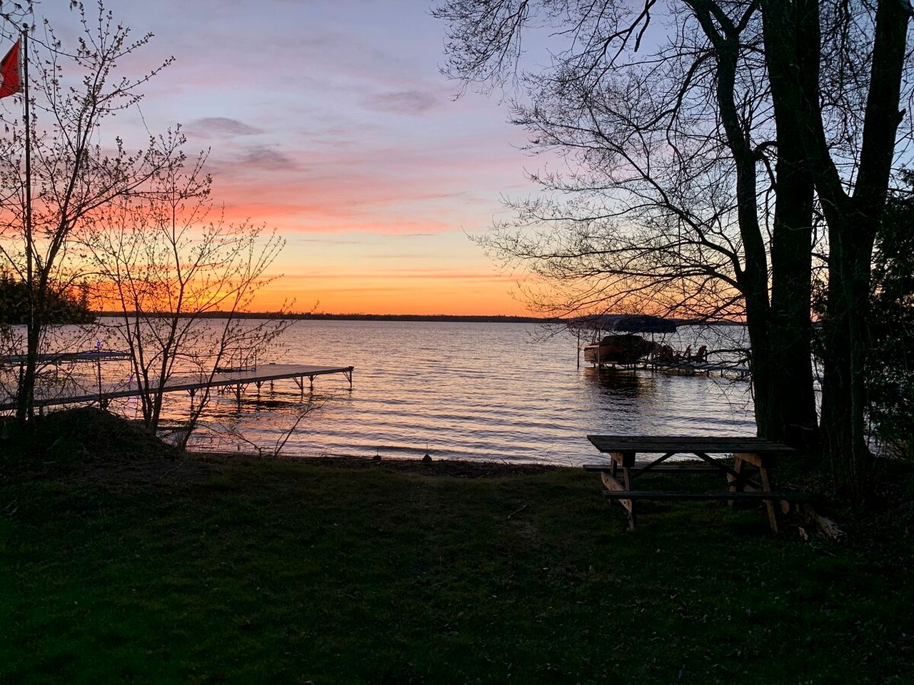 A lakeside view with picnic tables and a flag.