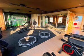 Een fitnessruimte met trainingsapparatuur, waaronder loopbanden en een hometrainer, en een spiegelwand.