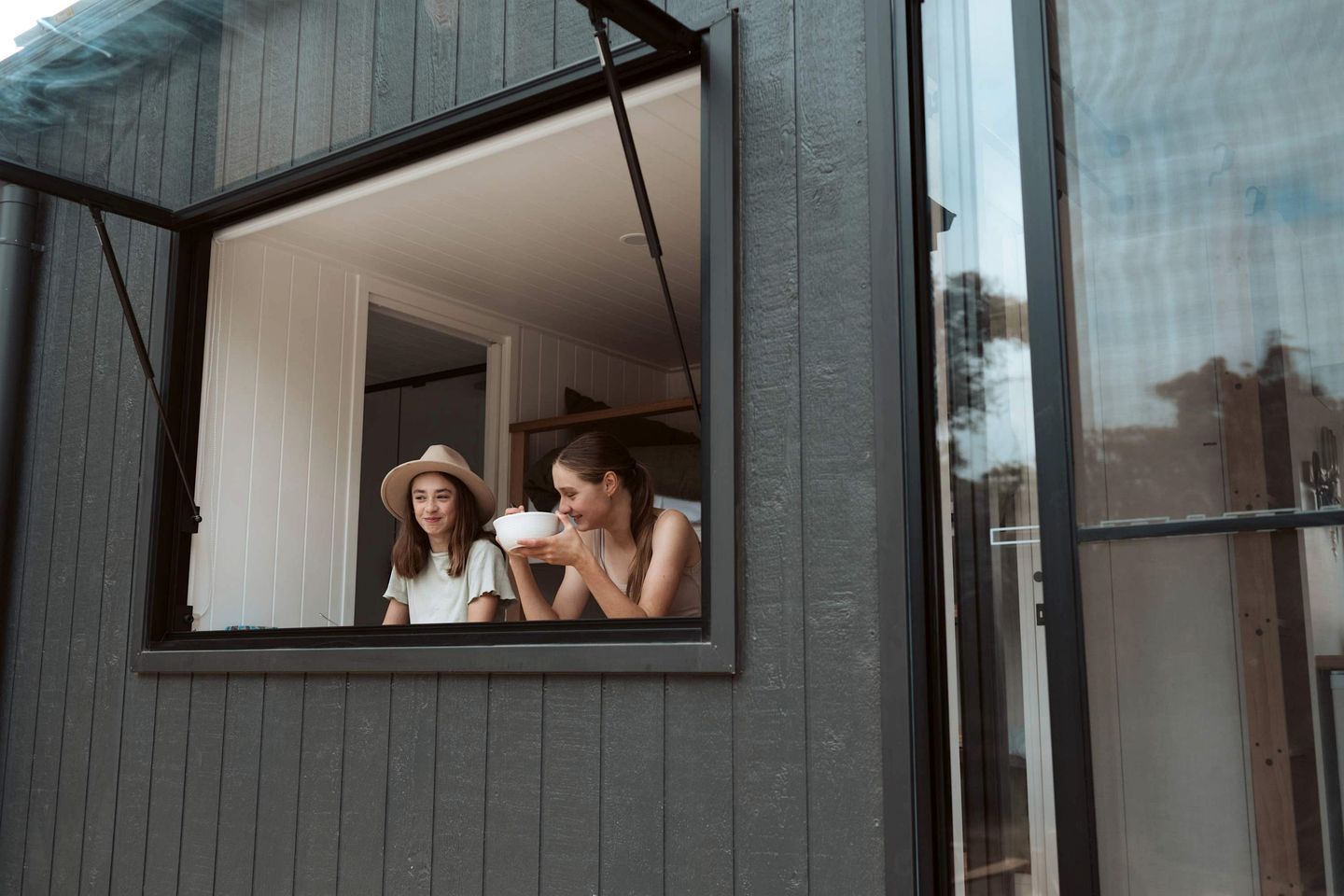A window with two people inside, one holding a bowl.