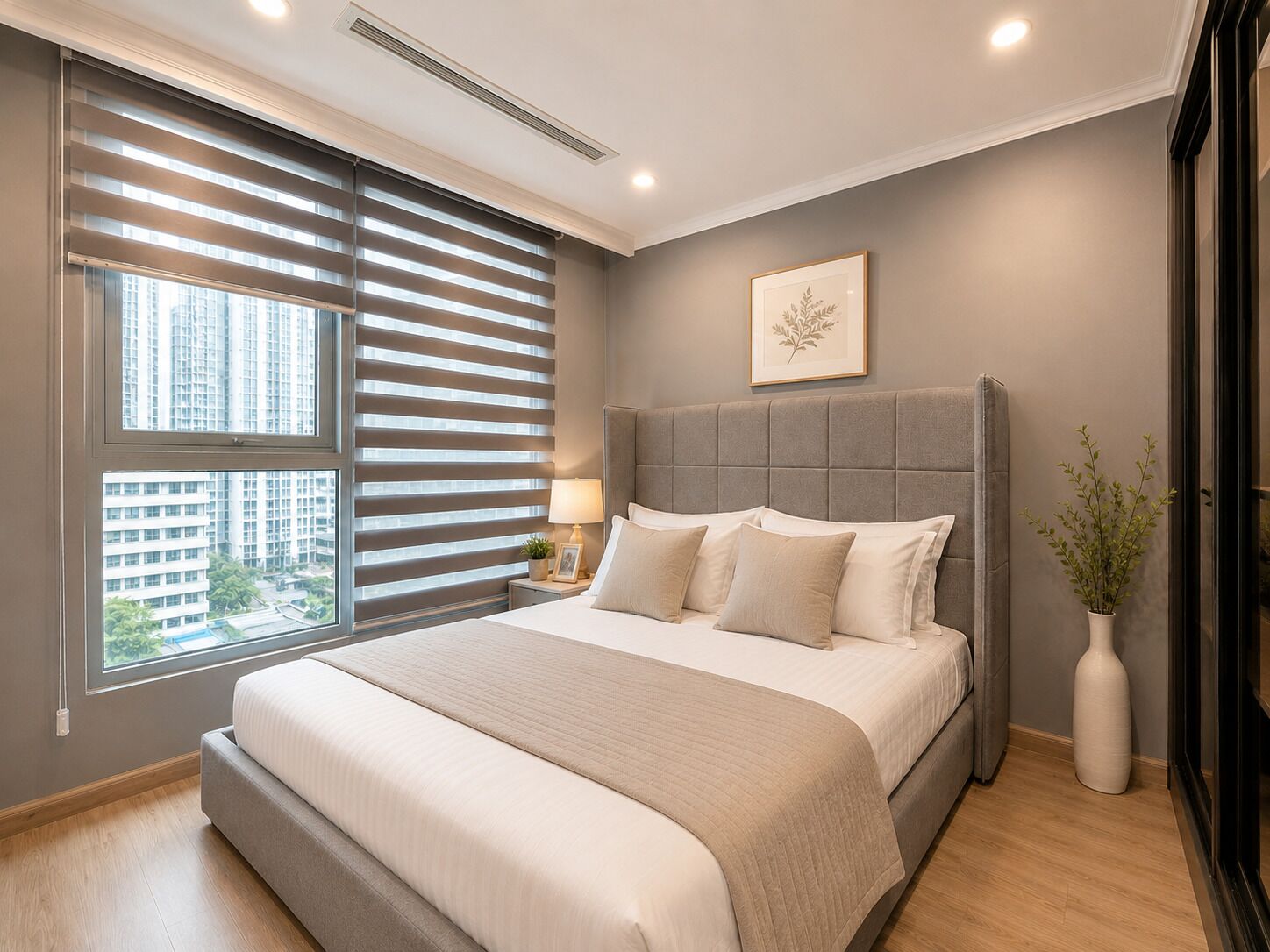 A modern bedroom with a large bed, a nightstand, a potted plant, and a window with blinds.
