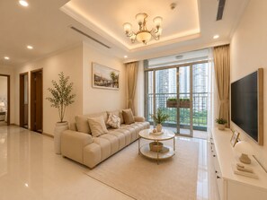 Ein modernes Wohnzimmer mit einer Couch, einem Couchtisch, einem Fernseher und einem großen Fenster mit Blick auf die Stadt.