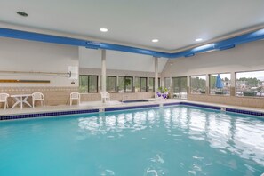 An indoor swimming pool with clear blue water, white chairs, and a view of buildings through large windows. - Keystone Lakefront Retreat! Pool & Hot Tub Access (Keystone)