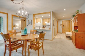 A spacious kitchen with wooden cabinets, a dining table with chairs, and a hanging light fixture. - Keystone Lakefront Retreat! Pool & Hot Tub Access (Keystone)