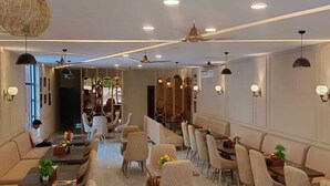 A modern hotel lobby with seating areas, a reception desk, and a view into the dining area. - MARINO WATERPARK AND RESORT (Bakshi Ka Talab)