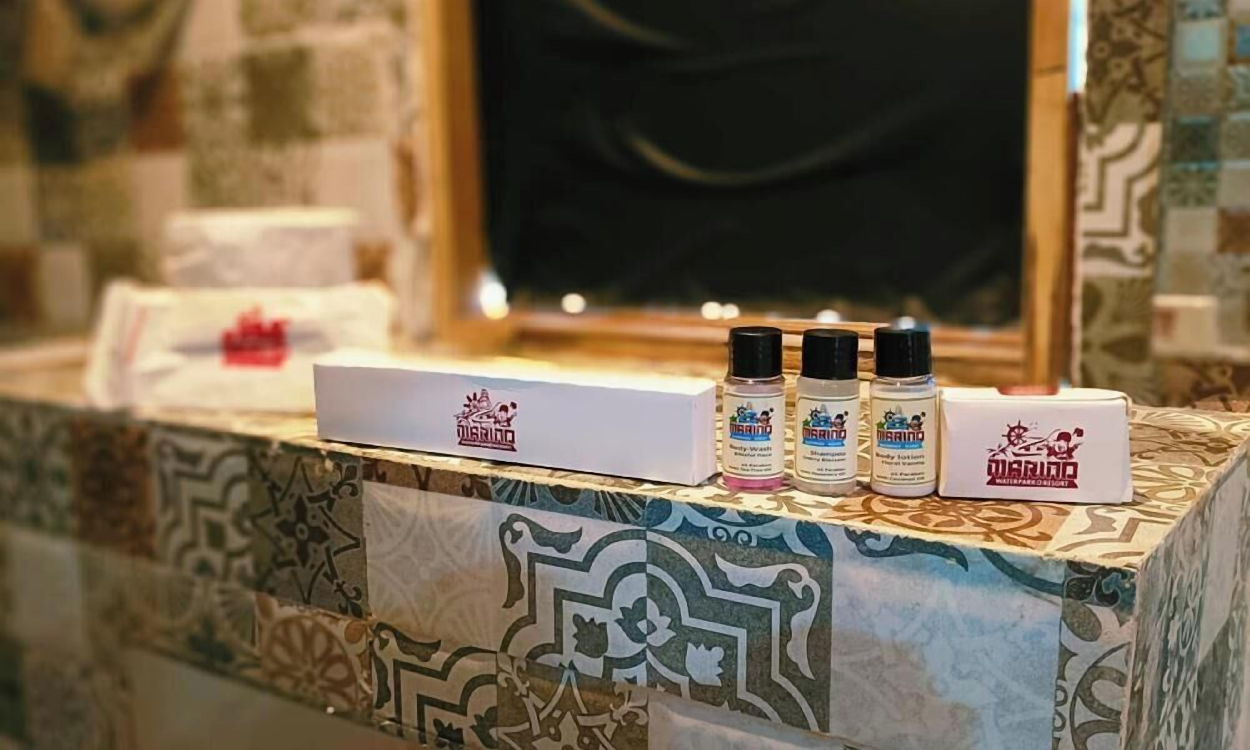 A bathroom counter with a tiled backsplash, a mirror, and three bottles of 'MARINO' body wash.