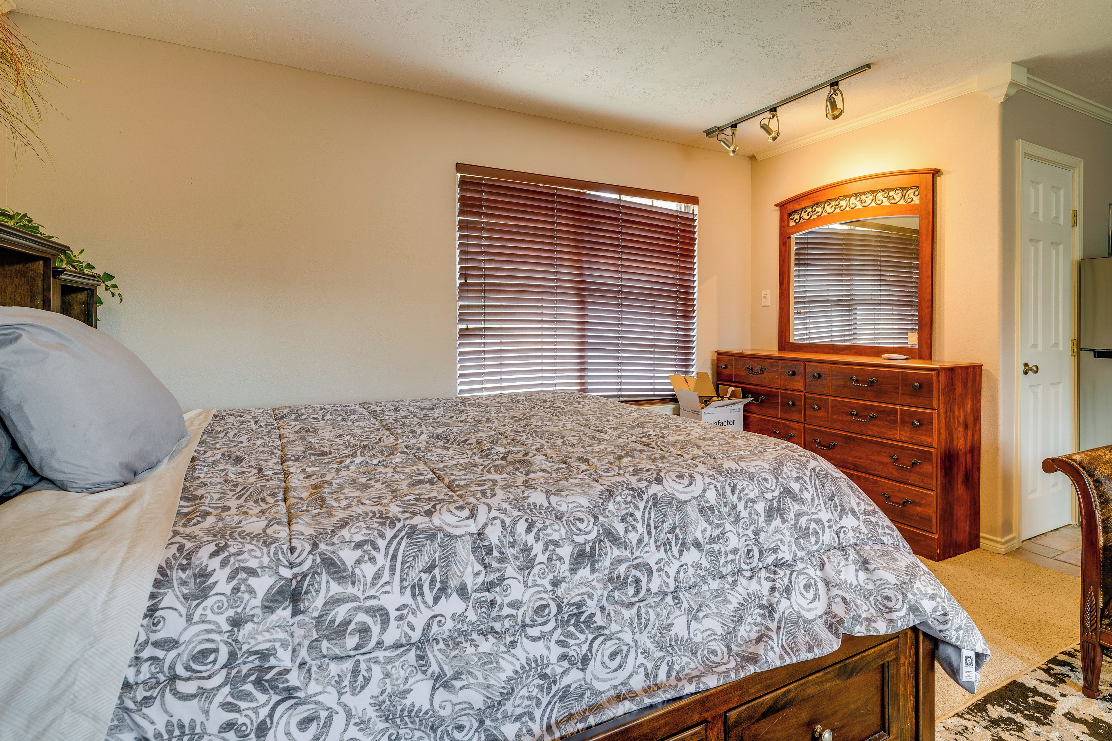 Ein Schlafzimmer mit Bett, Kommode, Spiegel und Fensterläden.