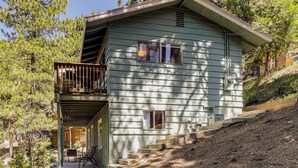 A two-story house with a balcony, a front porch, and a staircase leading up to the entrance. - Deck & Mtn Views! Woodsy Haven in Running Springs (Running Springs)