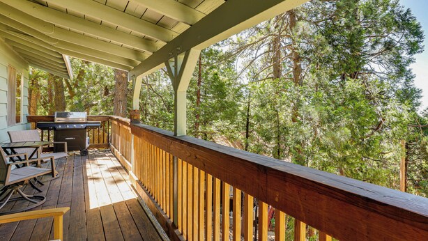 A covered outdoor deck with a grill, seating, and a view of a forest. - Deck & Mtn Views! Woodsy Haven in Running Springs (Running Springs)