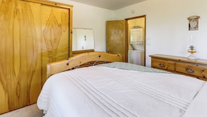 A bedroom with a wooden wardrobe, a bed with a white duvet, a dresser, and a mirror. - Deck & Mtn Views! Woodsy Haven in Running Springs (Running Springs)