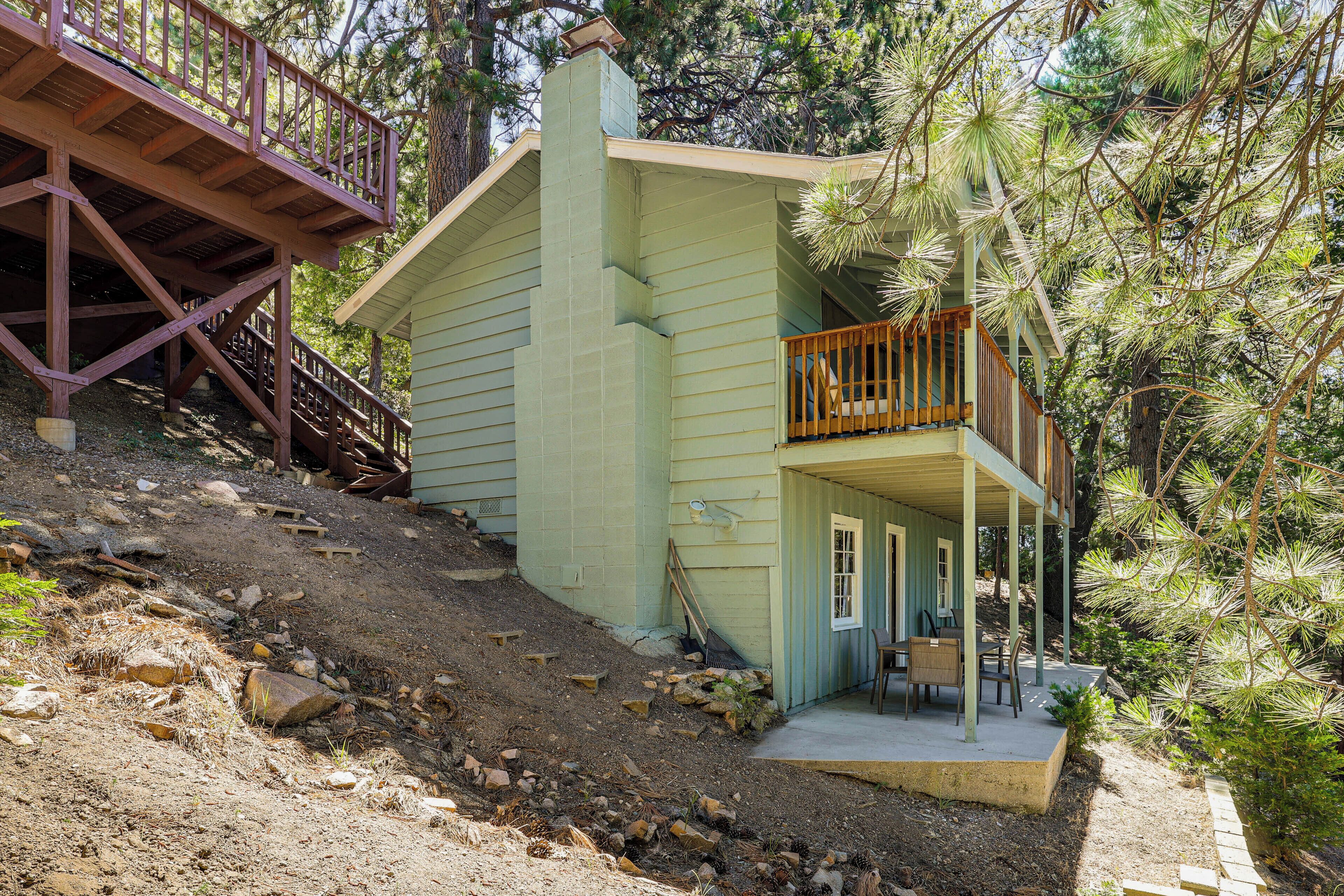 A two-story house with a balcony, surrounded by trees.