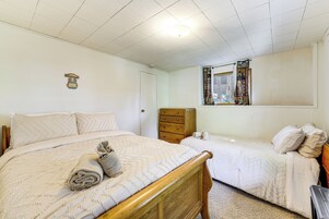 Un dormitorio con dos camas, un aparador de madera, una ventana con cortina e iluminación en el techo.