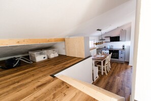 Eine kleine Küche mit Holzboden, einem Esstisch und weißen Schränken.