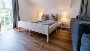 Ein Schlafzimmer mit einem Bett, Nachttischen, einem Sofa und einem Fenster mit Vorhängen.
