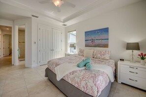 Un dormitorio con cama, mesita de noche y una pintura de una playa.