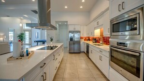 Una cocina moderna con electrodomésticos de acero inoxidable, armarios blancos y una isla central.