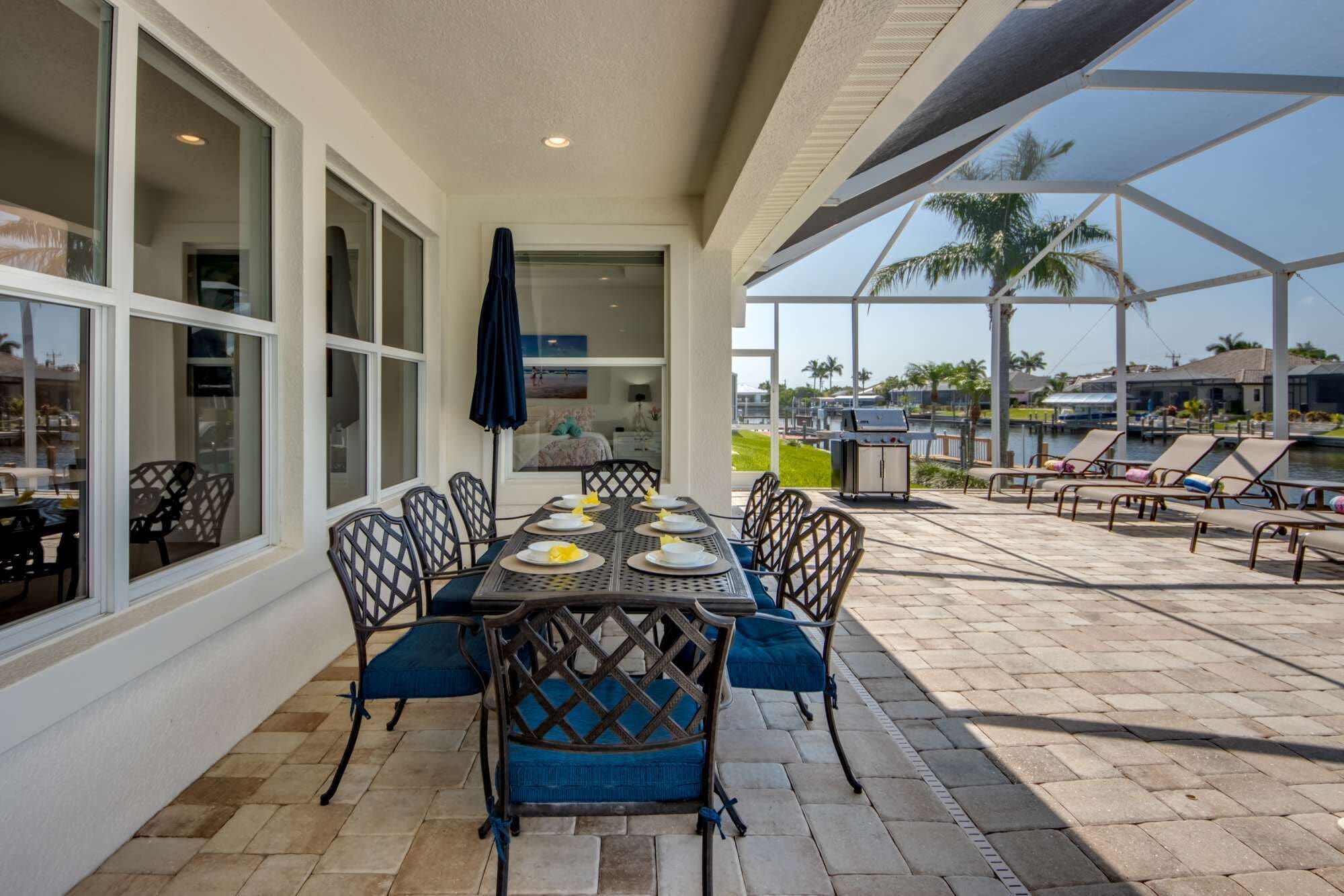 An outdoor dining area with a table and chairs, a grill, and a view of the marina.