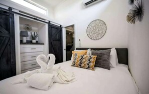 Ein Schlafzimmer mit einem Bett, Kissen, einem Handtuch, einer runden Wanddekoration und einer Schiebetür.