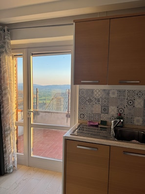 Una cocina con vista a un balcón, un salpicadero de azulejos y armarios de madera.