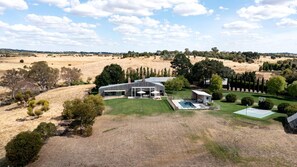 A modern house with a large lawn, a swimming pool, and a basketball court.