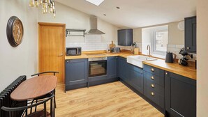 A modern kitchen with a wooden countertop, dark cabinets, a microwave, a toaster, and a sink.