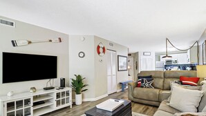 A living room with a flat-screen TV, a console table, a sofa, a coffee table, and a potted plant. - Ocean Oriented Oasis!  Indoor Heated Pool!  Pickleball! Hot Tub! (Hilton Head)