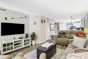 Ein Wohnzimmer mit Flachbildfernseher, einer Konsolentisch, einer Couch, einem Couchtisch und einer Topfpflanze.