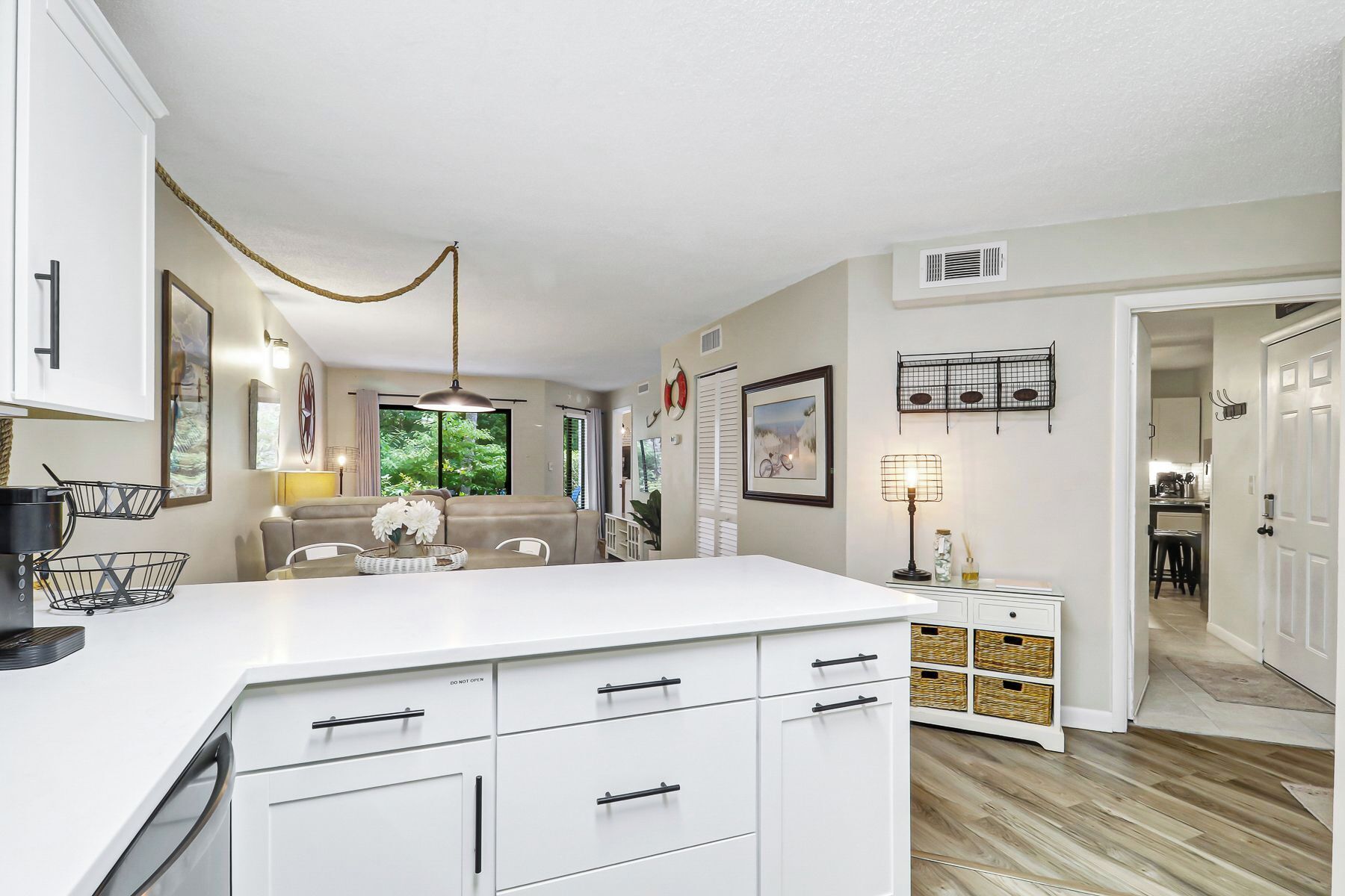 A modern kitchen with white cabinetry, a central island, and a dining area with a sofa.