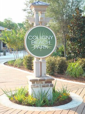 Ein Schild für den Coligny Beach Park mit kreisförmigem Design und Steinsockel.