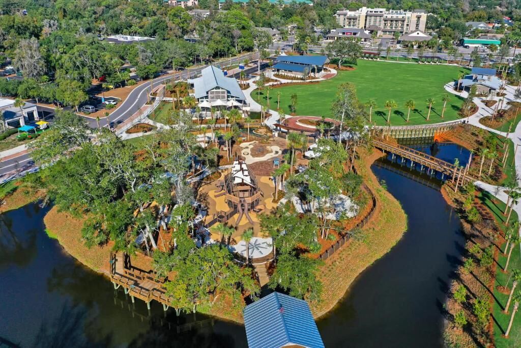 An aerial view of a theme park with a large building, a river, and a bridge.