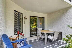 Eine Terrasse mit Tisch und Stühlen, ein blauer Stuhl und ein kleiner Holztisch mit Kerzen.