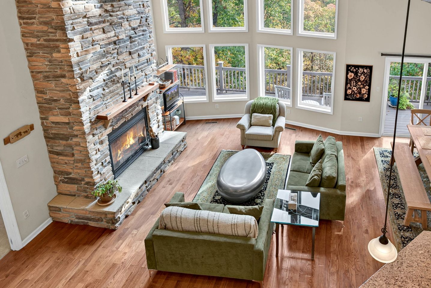 A spacious living room with a stone fireplace, large windows, and a cozy seating area.